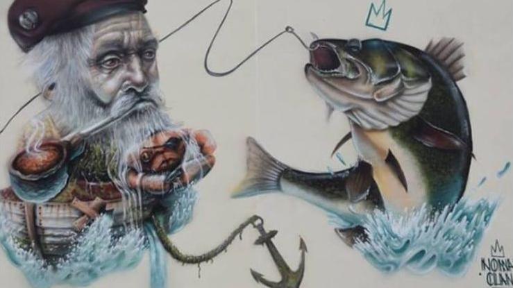 Street art showing a fisherman's head with his long white beard on a boat and a hook catching a fish which was painted on a building on Topping Street, Blackpool. 