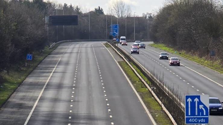 A three-lane motorway with no traffic one side on the other side traffic moves normally.