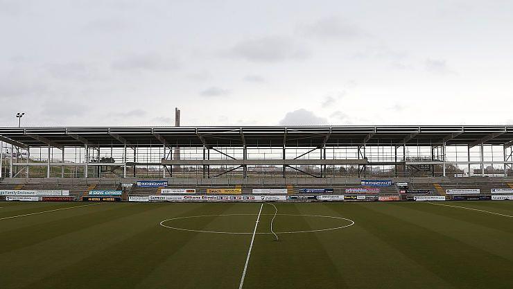 A football pitch with an unfinished stand in the background. 