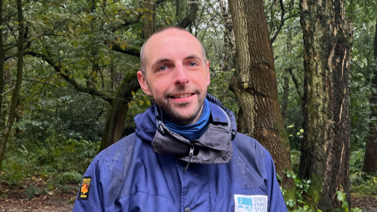 Dr Dan Scott, who has a shaven head and a beard and is wearing a blue waterproof coat with a Trent Rivers Trust logo on its front