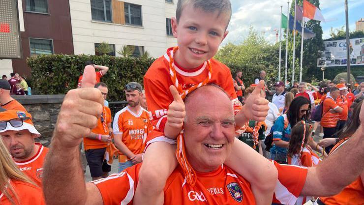 Man in Orange jersey with boy on his shoulders