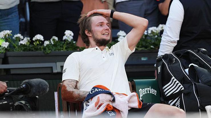 Alexander Bublik sits with his hand on his head after beating Jack Draper