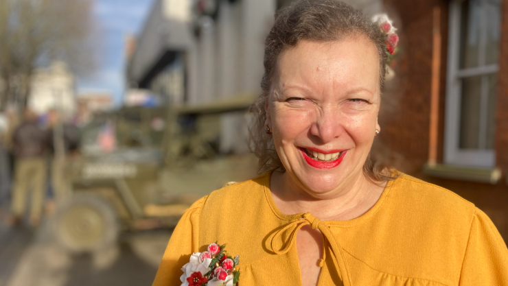 May Rose wearing a yellow top with a pink and white flower brooch 