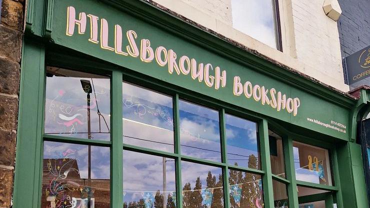 A green bookshop window at the front of the building with pink writing that reads: Hillsborough Books.