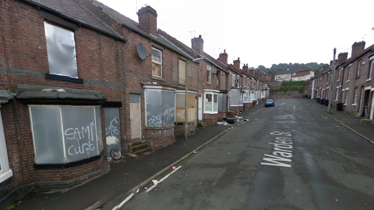 A Google Streetview shot of Warden Street in 2009. There are terraced houses either side of the street, many of which have been boarded up and vandalised