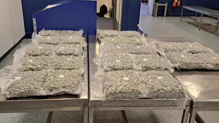 Twelve large vacuum sealed see-through bags of non-descript drugs lie in rows on large metal tables