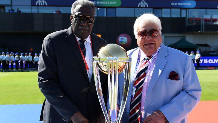 Clive Lloyd with greying hair (left) in dark suit Lancashire tie and white shirt and Farokh Engineer with white hair in a sky blue jacket white shit and club tie stand alongside the ICC Cricket World Cup trophy on the pitch at Old Trafford in Manchester.