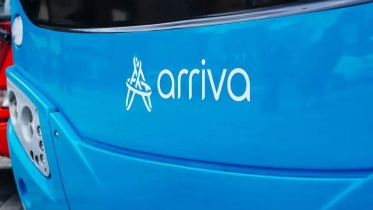 The front of a blue Arriva bus which has the company logo on it, a collection of circles intersecting to make a capital A, and the name of the company on it.