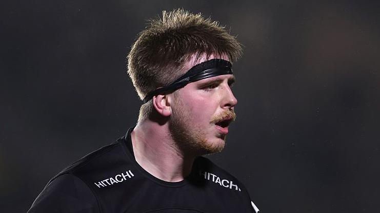 Finn Baker playing for Newcastle in a night match. He is wearing their black kit and a black headband