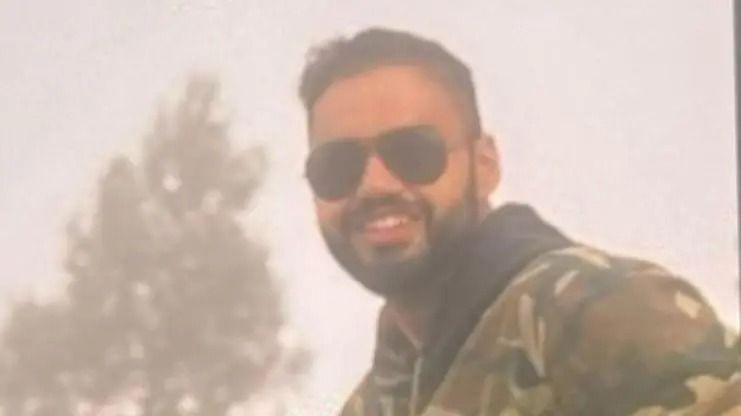 The photograph shows a bearded man, Vinay Narwal, wearing black sunglasses and a green camouflage jacket and posing for the camera
