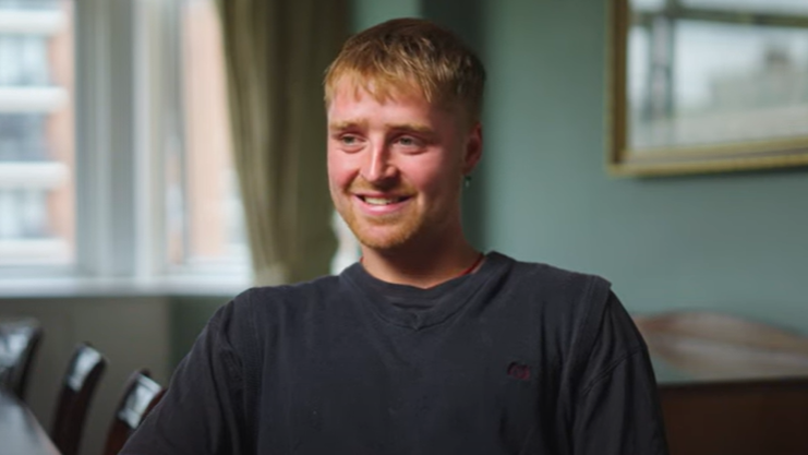 Seb looking and smiling at the camera with light hair and a navy t-shirt.