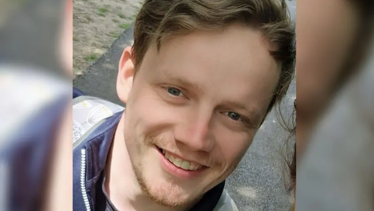 Craig Laurie smiles in a close up photo. He has wavy brown hair and a short brown beard, and is wearing a zip up jacket. 