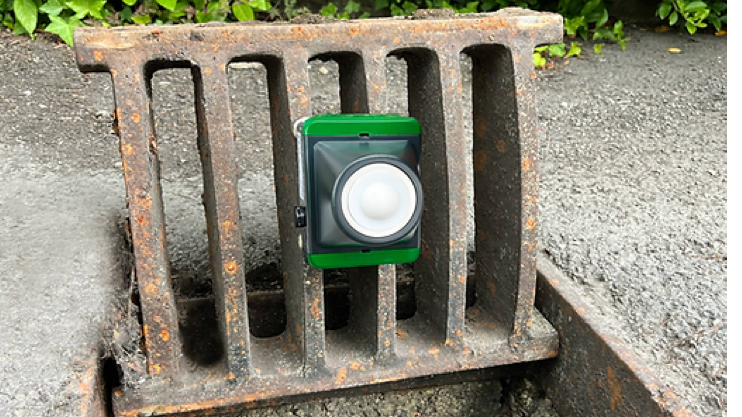 A green square sensor attached to a drain