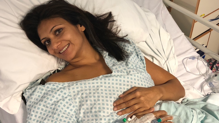 Anisha on a hospital bed, smiling to camera