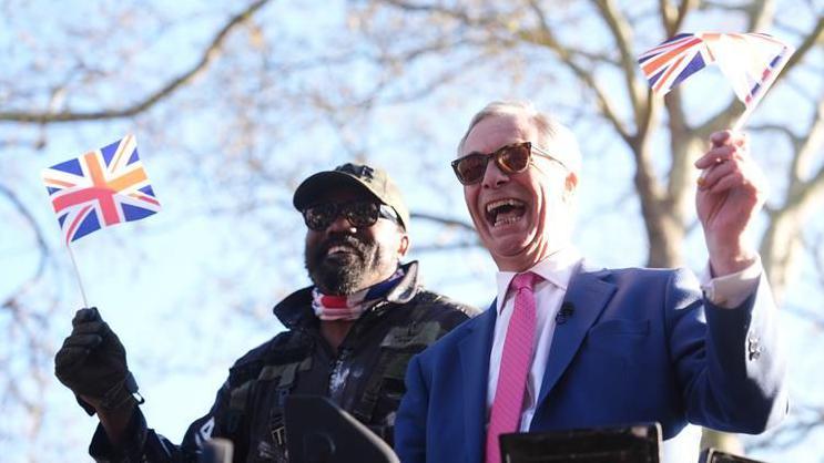Nigel Farage and Derek Chisora wave Union Jack flags from army tank