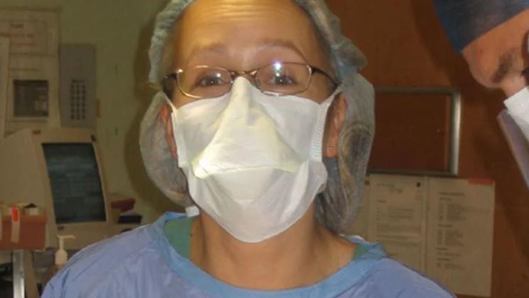 Orthopaedic surgeon Rachael Hutchinson in blue theatre scrubs and a mask