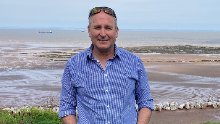 A man in a blue shirt by a beach