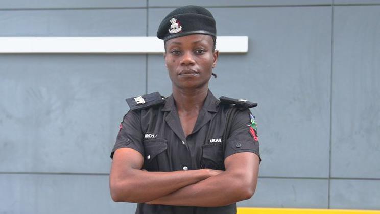 Juliet Ukah wears a black Nigeria Police uniform with a black beret and a black belt folding her arms