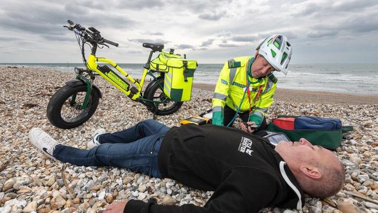 A SECAmb community first responder tends to a casualty on a shingle beach during a test run.