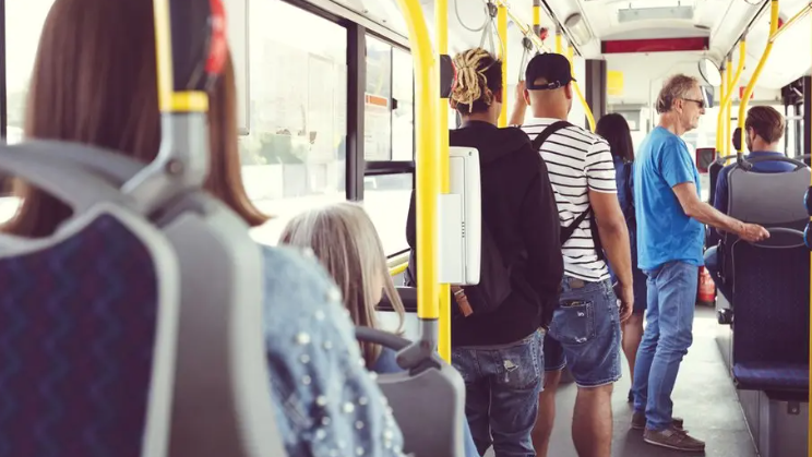 People stand and sit on a bus