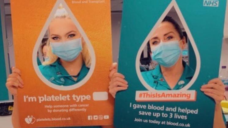 Somer Elliott holding a sign about platelet donating and her mother Anna Edwards is holding one saying 'This is amazing, I gave blood and helped save three lives'.