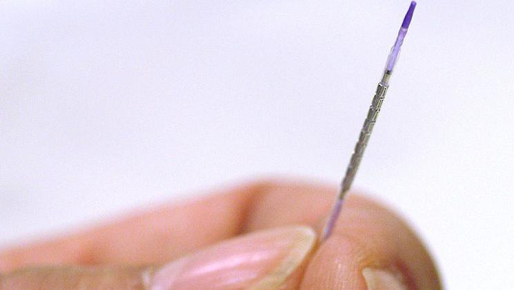 A tiny stent, with wire mesh around it, being held in a person's hand