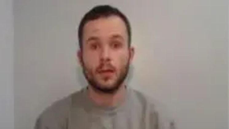 A mugshot of Jonathan Windsor who is wearing a grey sweatshirt and has a beard and a moustache and is pictured against a white background