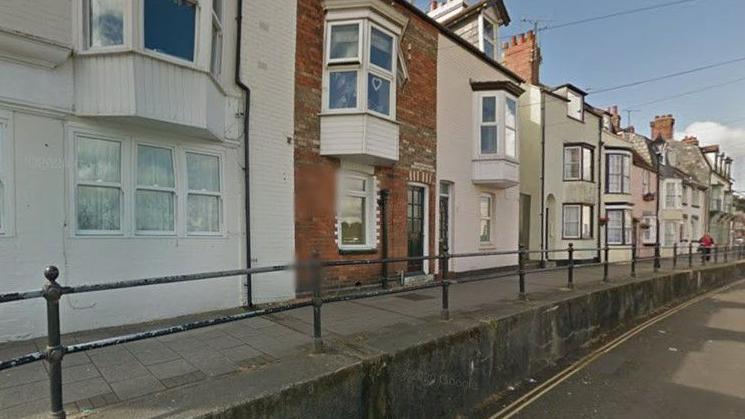 Terrace of houses with path with railings and road running in front.