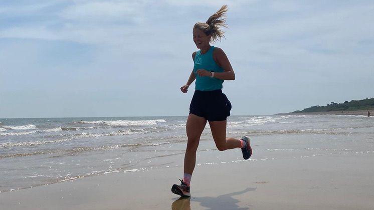 Megan Boxall was running on a beach next to the sea. She had long blonde hair in a pony tail and was wearing a blue vest top and black shorts and trainers.