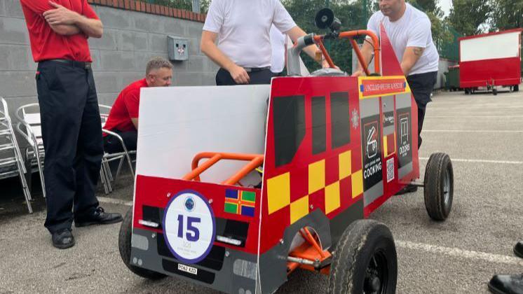 A Lincolnshire Fire and Rescue soapbox designed to look like a fire engine with black and yellow squares and fire warning signs