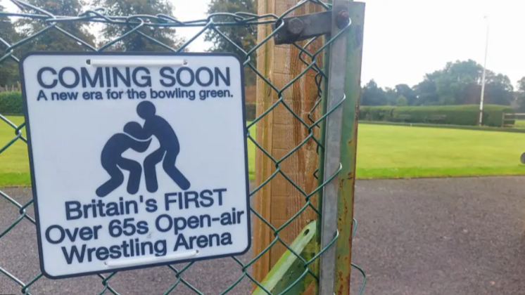 A joke sign reads: Coming soon. A new era for the bowling green. Britain's first over 65s open-air Wrestling Arena