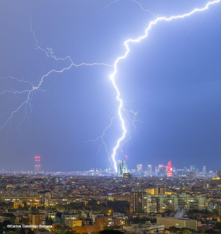 A powerful bolt of lightning slices through the night sky above Barcelona, illuminating the towering spires of the Sagrada Familia, the world’s largest unfinished Catholic church.