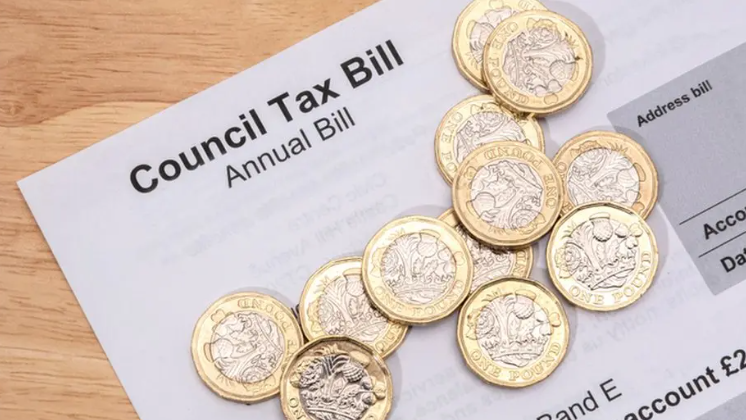 A council tax bill is pictured with pound coins on top