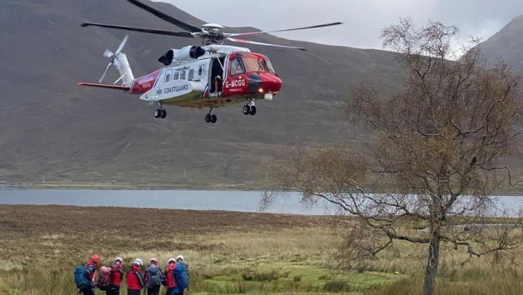 Luchd-teasairginn air an talamh le heileacoptair nam maor-cladaich os an cionn