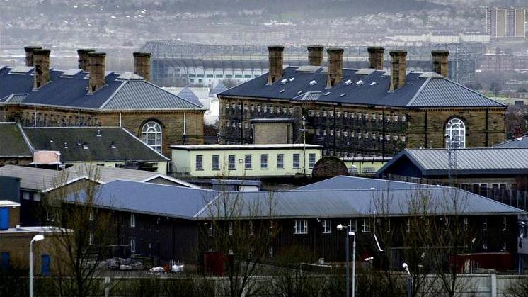 A view of Barlinnie prison showing the roofs of several buildings, with housing further away in the background