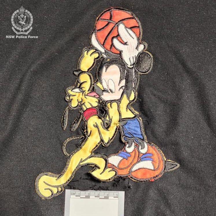 A black Mickey Mouse T-shirt with a hole in the middle and an evidence card placed on it