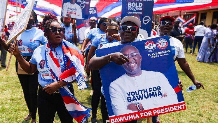 Supporters hold a placard depicting the portrait of Mahamudu Bawumia in Takoradi on 18 August 2024