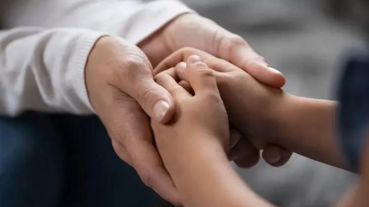 A close up of an adult's hands holding a child's hands. 