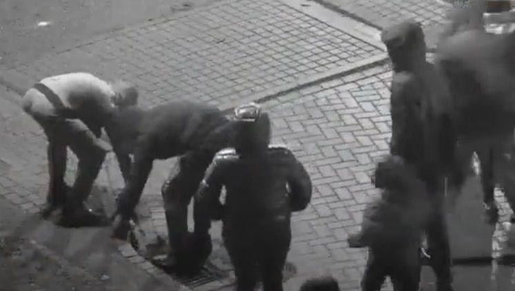 A group of youths on CCTV bending down to pick up rocks