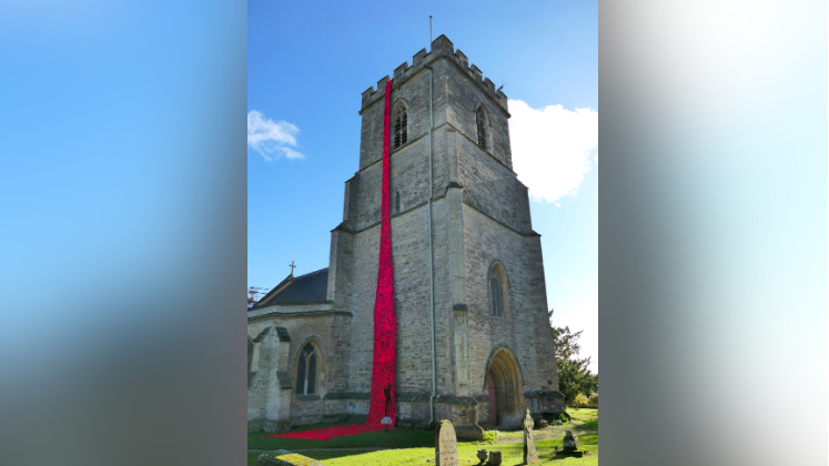 The cascade hanging at the side of the church on a sunny day. Several graves can be seen as well.