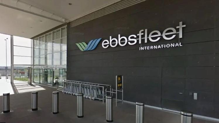 Interior of Ebbsfleet International stations with a big Ebbsfleet sign on the wall in silver and silver barriers and a big glass window at the rear