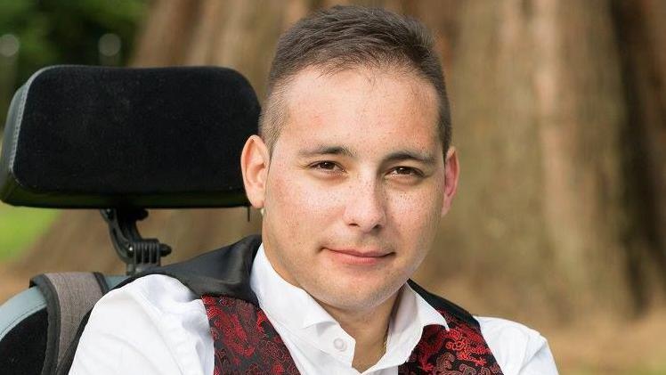 Karl Lee wearing a white shirt and red, printed waistcoat.