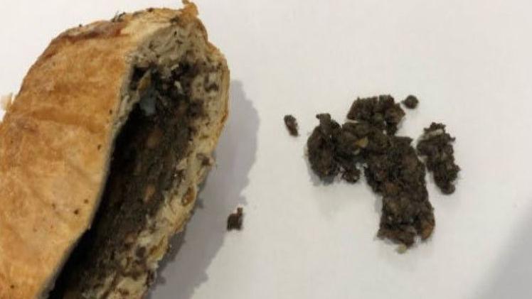 Beef Wellington cut open with filling exposed on left of image and some of the filling out on the right