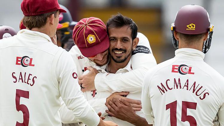 Yuzvendra Chahal is hugged by his Northamptonshire team-mates after taking a wicket