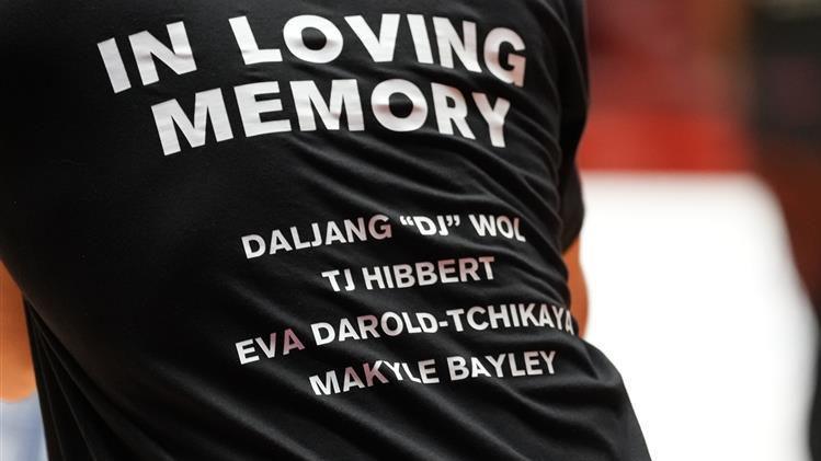 A person wearing a black t-shirt with "in loving memory" and the names of four car crash victims.