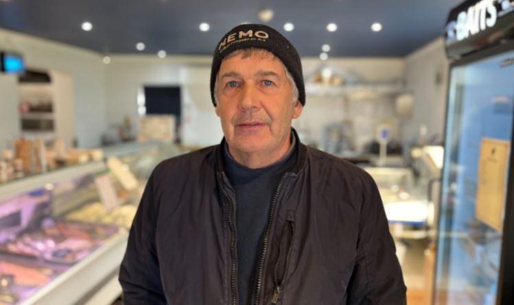 Man in a hat with the words 'NEMO' written on it posing at a fish counter