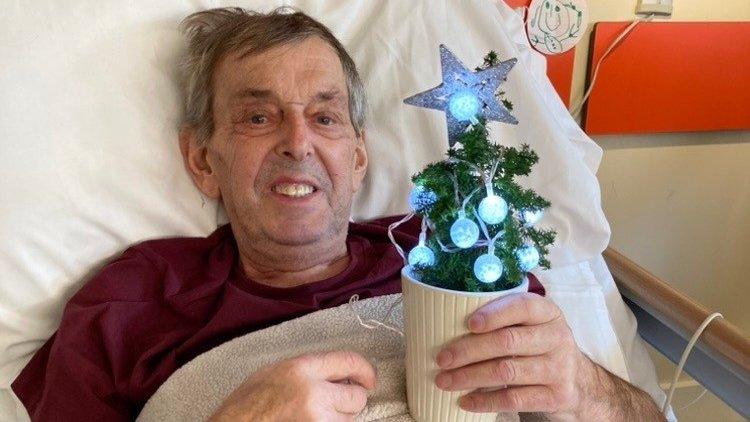 John Hunt holding a miniature Christmas tree at the inpatient ward