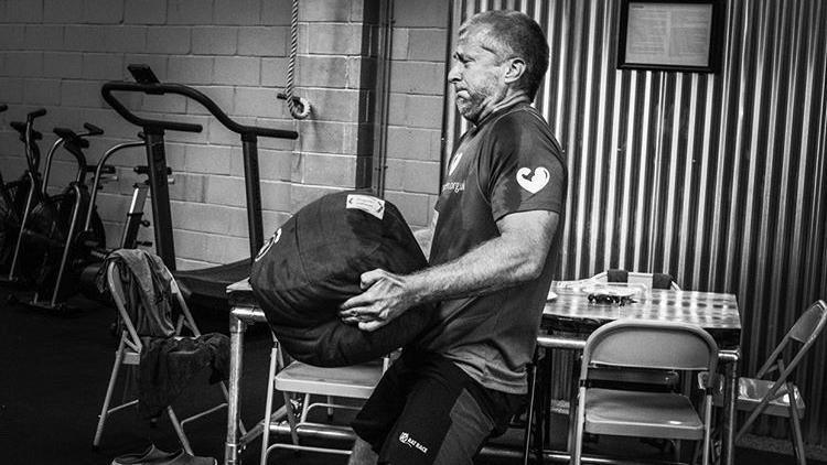 A man trains at a gym holding a heavy object 