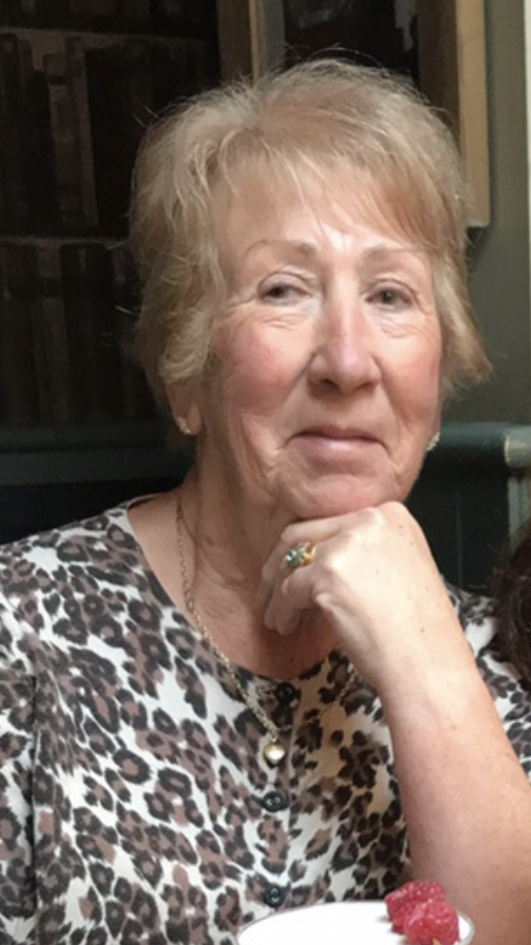 A picture of a pensioner with blonde hair and a leopard skin print t-shirt smiling at the camera.