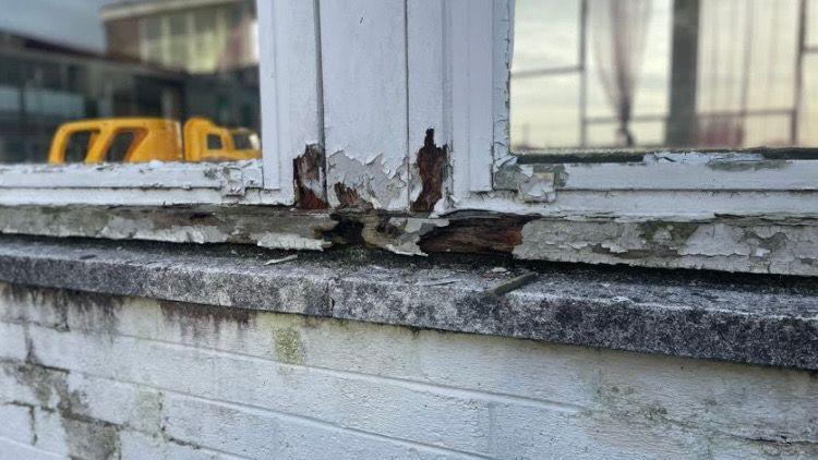 A close up image of deteriorating and crumbling white window panes.